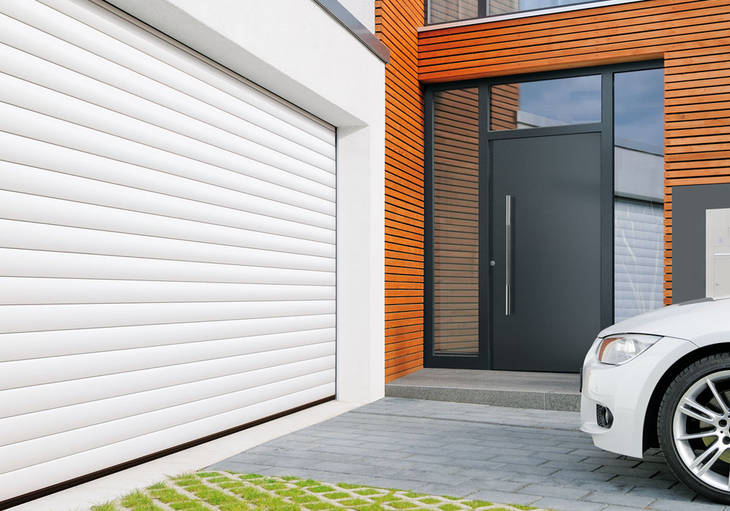 Na zdjęciu widać dom wyposażony w rolowaną bramę garażową firmy Hormann w kolorze białym oraz drzwi wejściowe firmy Hormann w kolorze antracyt